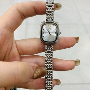 Close-up of small silver square dial watch with Roman numerals and metal mesh bracelet