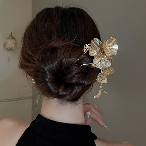 Detail showing a golden floral hair stick with tassels and rhinestones on hair