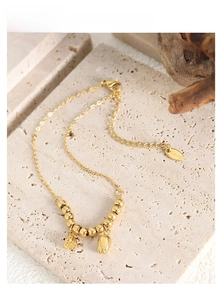 Detail of gold stainless steel beaded chain with lotus and tulip flower pendants