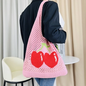 Detailed knit texture of pink hollow tote bag with red cherry embroidery worn by a model