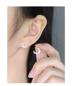 Detailed close-up of crescent moon stud earrings with molten texture on finger