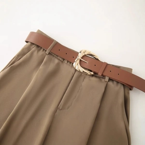 Ceinture en cuir marron avec boucle dorée texturée sur un pantalon en satin élégant