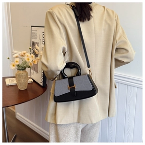 Detail of the elegant box bag with metallic H-clasp and a unique curved handle