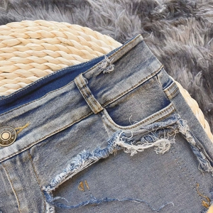 Nahaufnahme der dunkelblauen Denim-Shorts mit ausgefransten Kanten und einem Metallknopf