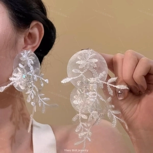 Close-up of elegant white floral lace embroidery earrings on model for vacation style