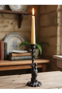 Détail d'un bougeoir en fonte noire vintage avec des sculptures de personnages raffinées