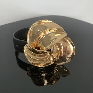 Macro-opname van een grote gouden metalen bloemknoop op een zwarte leren armband