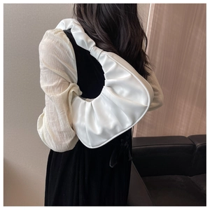 White pleated crescent shoulder bag shown on model for stylish underarm aesthetic