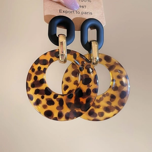 Detailed close-up of leopard print acrylic hoop earrings with a triple-ring nested design
