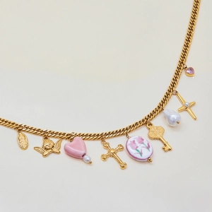 Detail of gold chain necklace with angel, pink heart, cross, and pearl charms