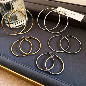Minimalist round hoop earrings set in gold and silver finishes on a textured tray