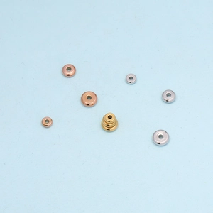 Flat lay of stainless steel saucer beads in gold, silver and rose gold finishes on blue