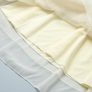 Close-up of the light yellow chiffon dress hem with delicate double-layer ruffles