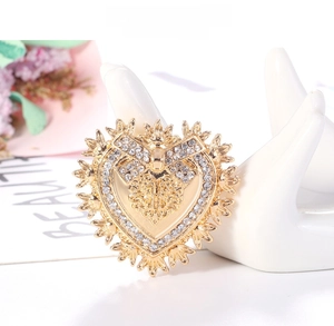 Detailed close-up of Baroque gold heart brooch with rhinestones on ceramic display