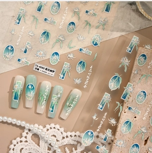 Macro detail of 5D embossed nail stickers featuring blue floral motifs and calligraphy
