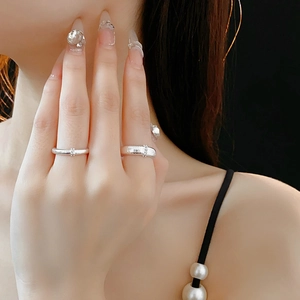 Dettaglio di anelli in argento spazzolato con zirconi sulle dita per un look elegante