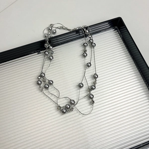 Detail of elegant multi-layered grey pearl necklace on a clear ripple tray