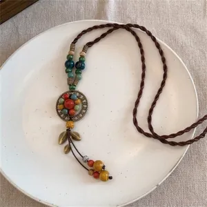 Gros plan du pendentif fleur bohème avec perles en céramique colorées et pompons bronze