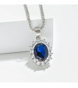 Macro shot of oval blue sapphire pendant with white zircon halo on white geometric steps