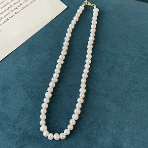 Detail of natural baroque freshwater pearls necklace with gold buckle on dark fabric