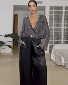 Detail of dark grey sequin V-neck wrap top paired with black wide-leg satin trousers
