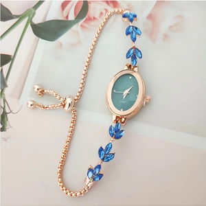 Detail of rose gold leaf bracelet watch with green dial and blue crystal accents
