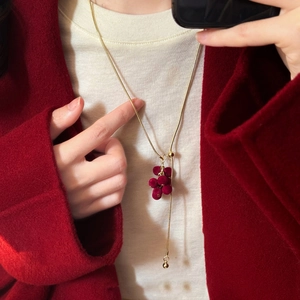 Close-up of red flocked grape tassel necklace on a dark red winter wool coat