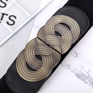 Detail of wide black elastic belt featuring vintage bronze woven metal buckle on marble