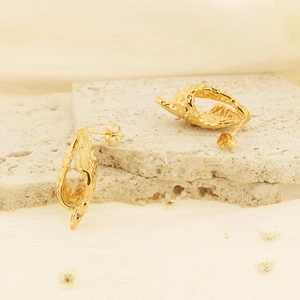 Détails de boucles d'oreilles dorées géométriques avec texture plissée sur pierre