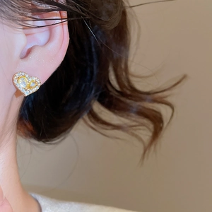 Close-up of elegant gold-plated heart stud earrings with cubic zirconia on a model
