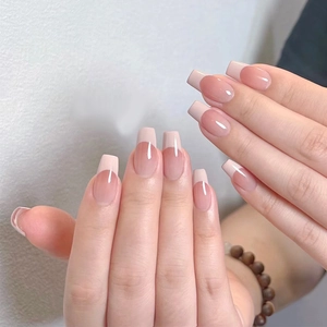 Close-up of nude French tip press-on nails in medium square shape with white tips