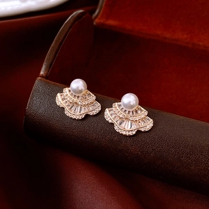 Detail of vintage fan-shaped earrings with pearls and zircons on a classic jewelry box