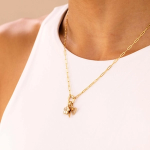 Gold paperclip chain necklace featuring lucky clover, key, and heart charms on a model