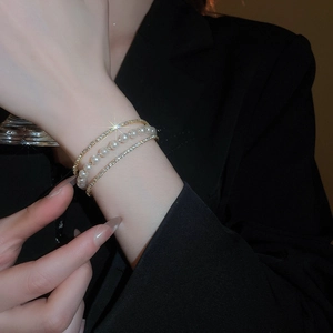 Detail view of a triple-layer bracelet featuring white pearls and sparkling rhinestones