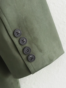 Detail of olive green suede blazer cuff showing four charcoal resin buttons on a textured fabric
