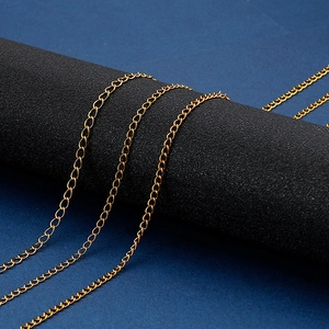 Detailed close-up of three gold stainless steel curb chains on dark props