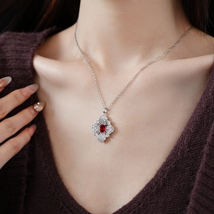 Detail of silver necklace with red rectangular gemstone and white zircon flower pendant