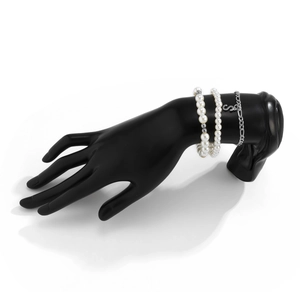 Detail of three-layer beaded bracelet set with pearl accents and a silver S pendant
