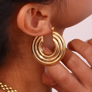 Detailed macro view of triple-layered gold plated hollow hoop earrings with thick texture