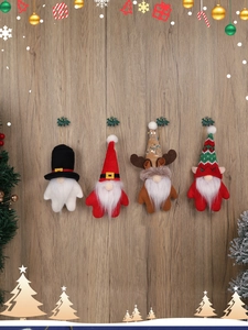 Détail de quatre ornements de gnomes de Noël suspendus sur fond de bois clair