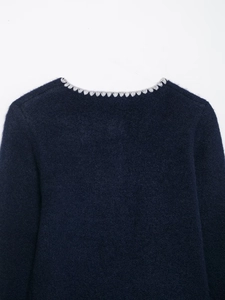 Detail of navy knit sweater showing scalloped grey crochet neckline and fuzzy texture