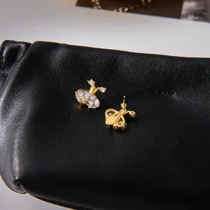 Detail of bee stud earrings with gold plating and sparkling zircon stones on leather