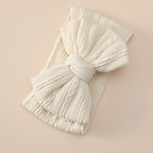 Macro shot of cream cable knit baby headband with a large decorative soft bow detail