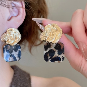 Detailed view of vintage gold textured metal and square leopard print acrylic drop earrings