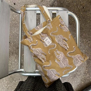 Sac cabas en toile jaune moutarde avec imprimé léopard et bandoulières sur une chaise