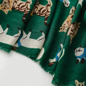 Detail view of dark green scarf with cartoon cat print and delicate short fringes