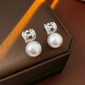 Macro shot of pearl drop earrings with crystal pave on textured jewelry box