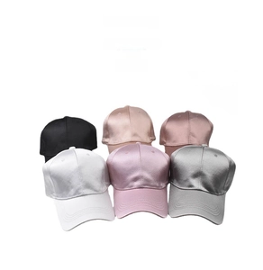 Detail view of colorful satin baseball caps showing smooth glossy fabric and six-panel design