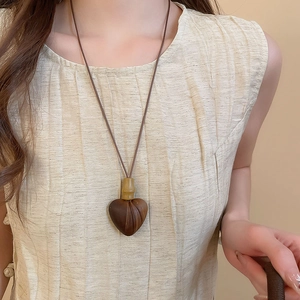 Detail of a vintage heart-shaped wooden pendant necklace with bamboo accents and brown cord