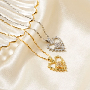 Close-up of gold and silver heart pendants with zircon stars on silk background